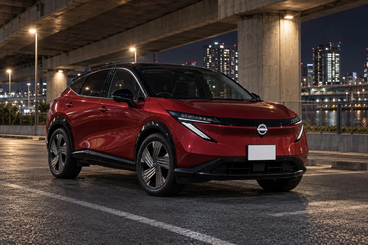 日産 アリア B9(2026年マイナーチェンジ後)の斜め前からの外観。ボディと同じ色のフロント部、19インチアルミ。ボディカラーはディープクリムゾン/ミッドナイトブラックの2トーン。夜の都市の高架下の駐車場に停まっている