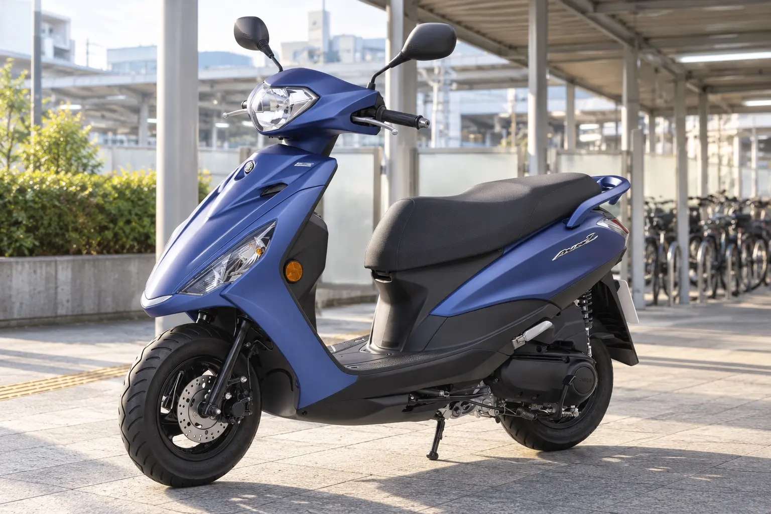 ヤマハ アクシスZを斜め前から見たカット。マットのブルーの車体、すっきりしたヘッドライト、長いシート、平らな足元、前後10インチのホイール