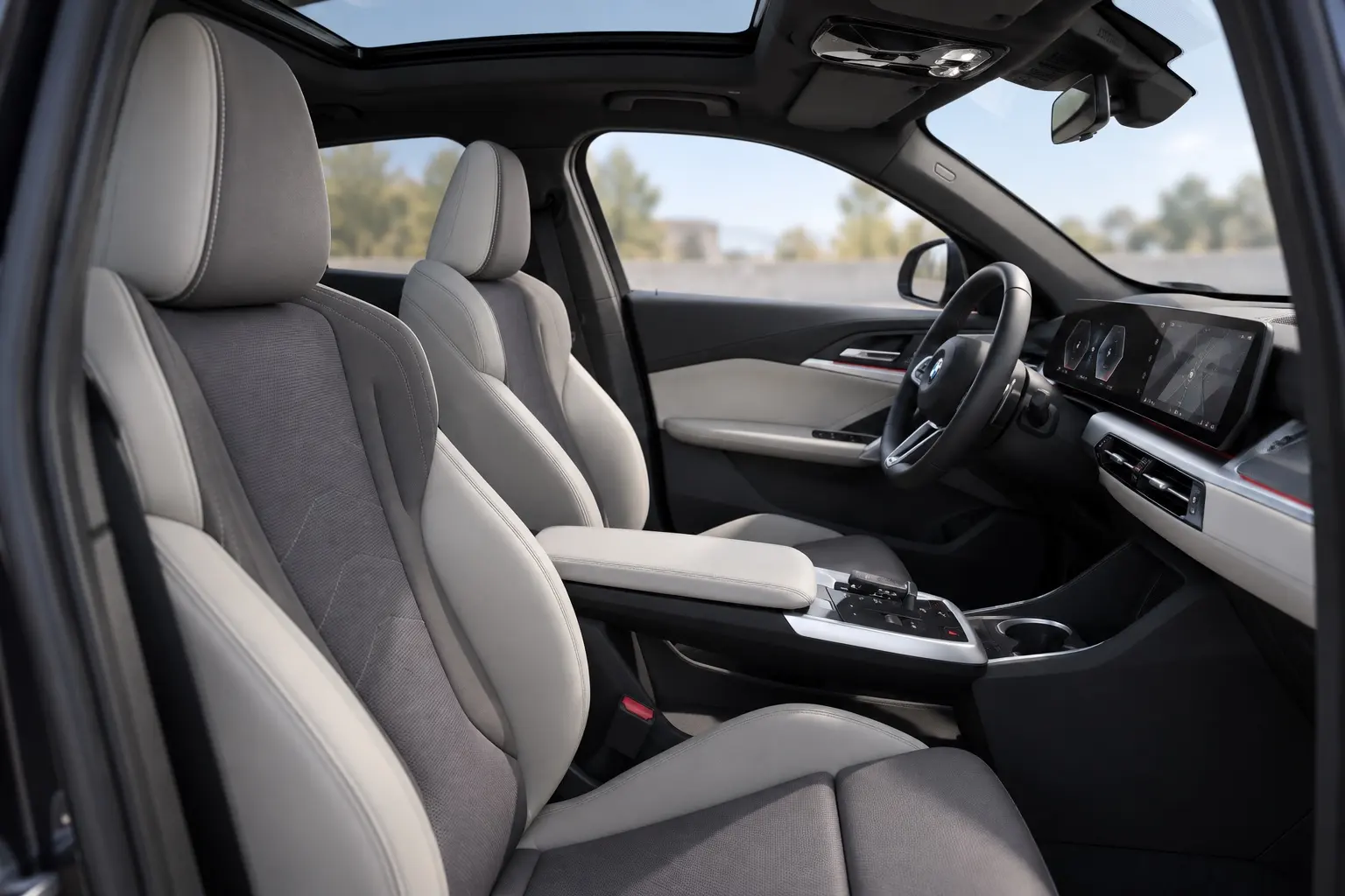 BMW X2（U10型）の運転席と助手席の実車イラスト。明るいグレーのスポーツシート、横に長い曲面ディスプレイ、浮いたセンターコンソール、ガラスルーフからの光