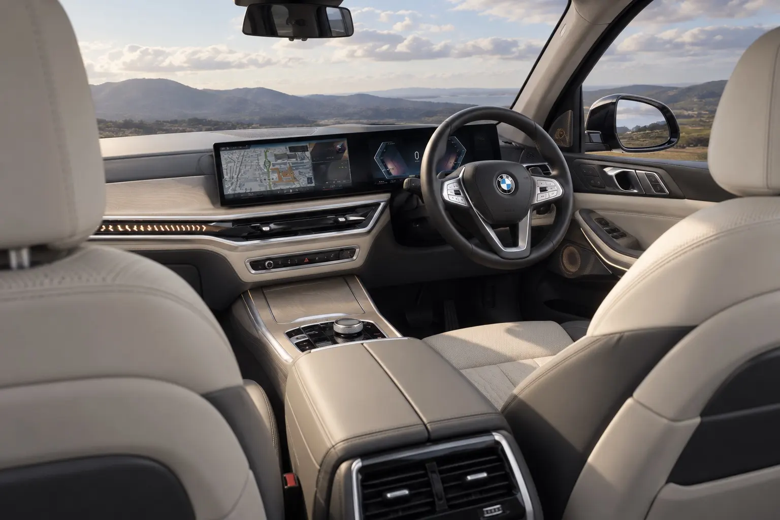 BMW X7（G07型）のコックピットの実車イラスト。横長の曲面ディスプレイ、明るい木目のパネル、ベージュのレザーシート。日本仕様の右ハンドル