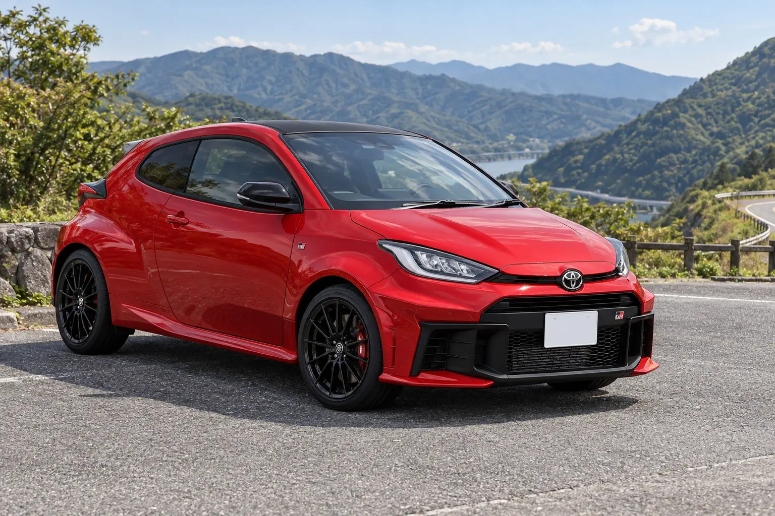 トヨタ GRヤリス RZ“High performance”(2026年モデル)の斜め前からの外観。ボディカラーはエモーショナルレッドII。山あいのワインディングの展望駐車場に停まっている