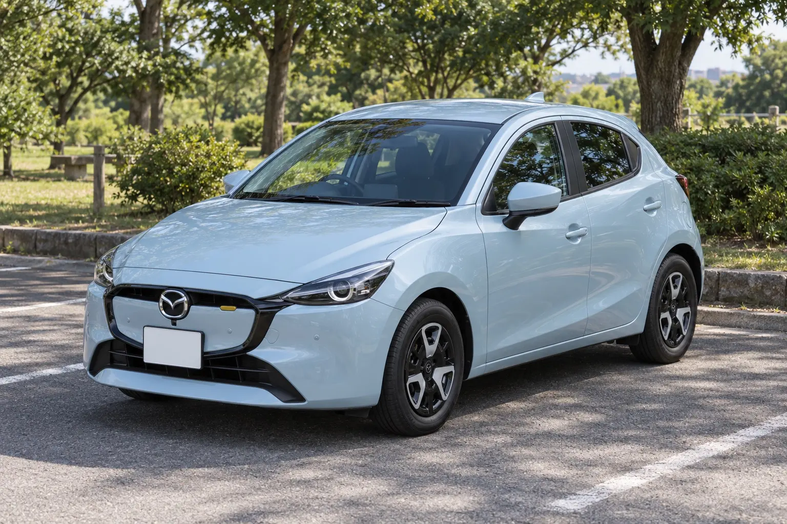マツダ MAZDA2 15BD i Selection II（2025年改良後）の斜め前からの外観。ボディカラーはエアストリームブルーメタリック。公園のそばの駐車場、晴れた午前の光