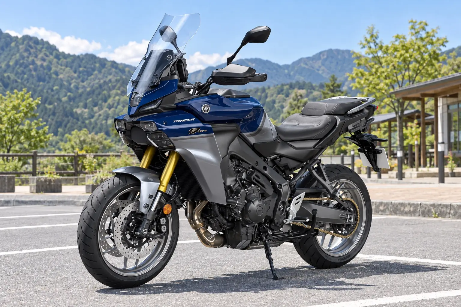 ヤマハ TRACER9 GT+ Y-AMTを斜め前から見たカット。濃い青の車体、大きなスクリーン、細いヘッドライト、サイドケースを付けていない姿、直列3気筒エンジン