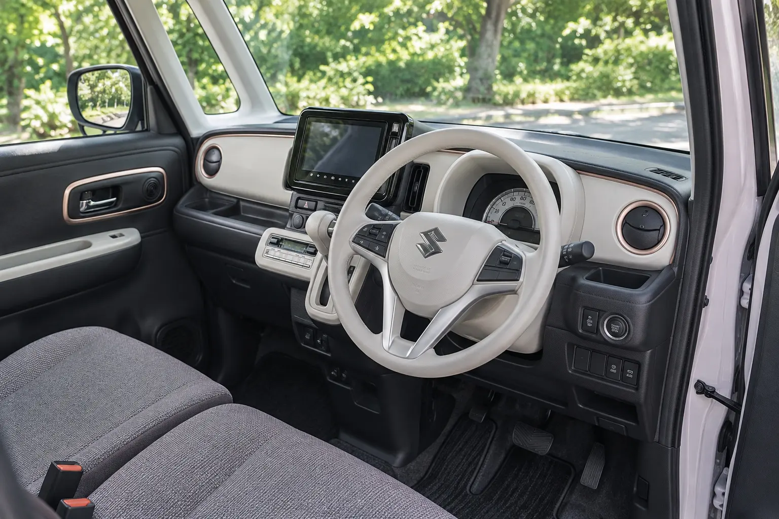 運転席側から見たスズキ ワゴンR スマイルの室内。インパネ、ステアリング、メーカーオプションのナビ、窓の外の緑の木々